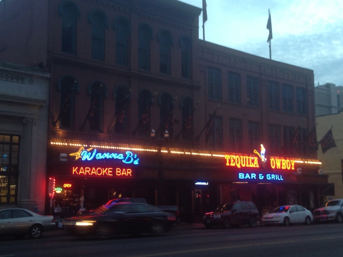 The bright neon signs of Wanna B's Karaoke Bar and the Tequila Cowboy on Broadway in downtown Nashville, Tennessee.
